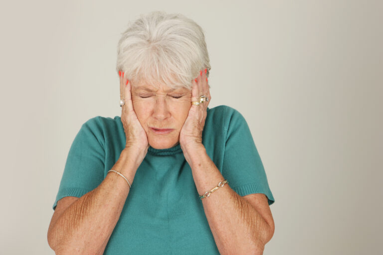 Older woman covering her ears with her hands.