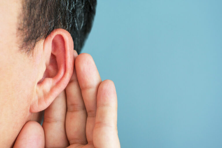 Close up of man holding hand behind ear to hear